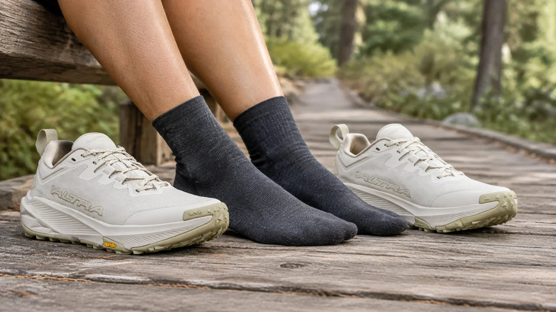 Hiker wearing socks and tan Altra trail shoes on a woodland trail