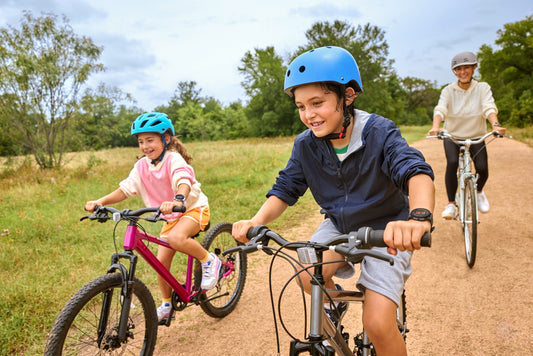 Children wearing Garmin Bounce 2 watches ride bikes with an adult