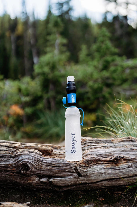 Sawyer Squeeze with CNOC bottle outdoors on a log