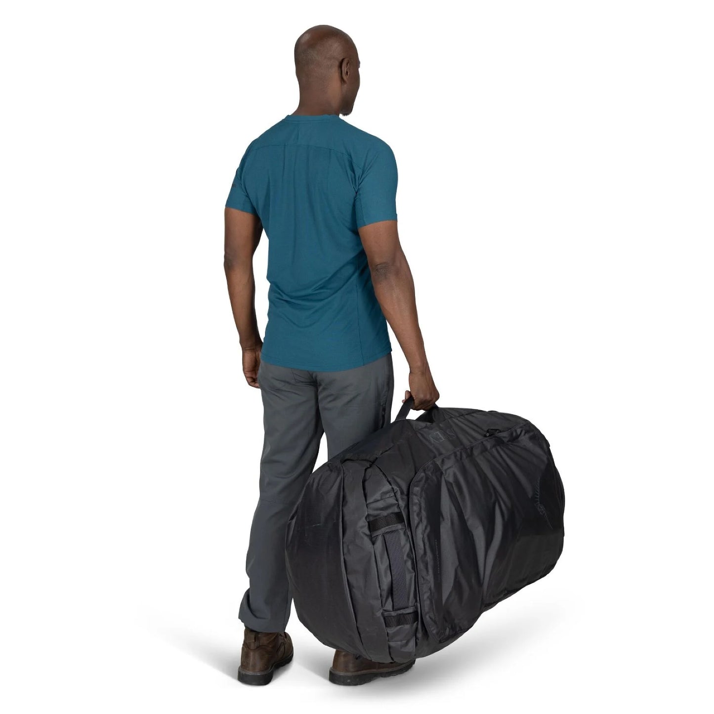 Man holding the Osprey Transporter Duffel 150 from the back handle while walking